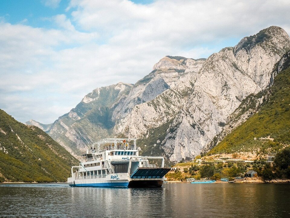 a ferry in Komani Lake between mountains